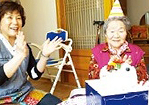 요양사와 할머니가 생일파티를 하고 있는 사진